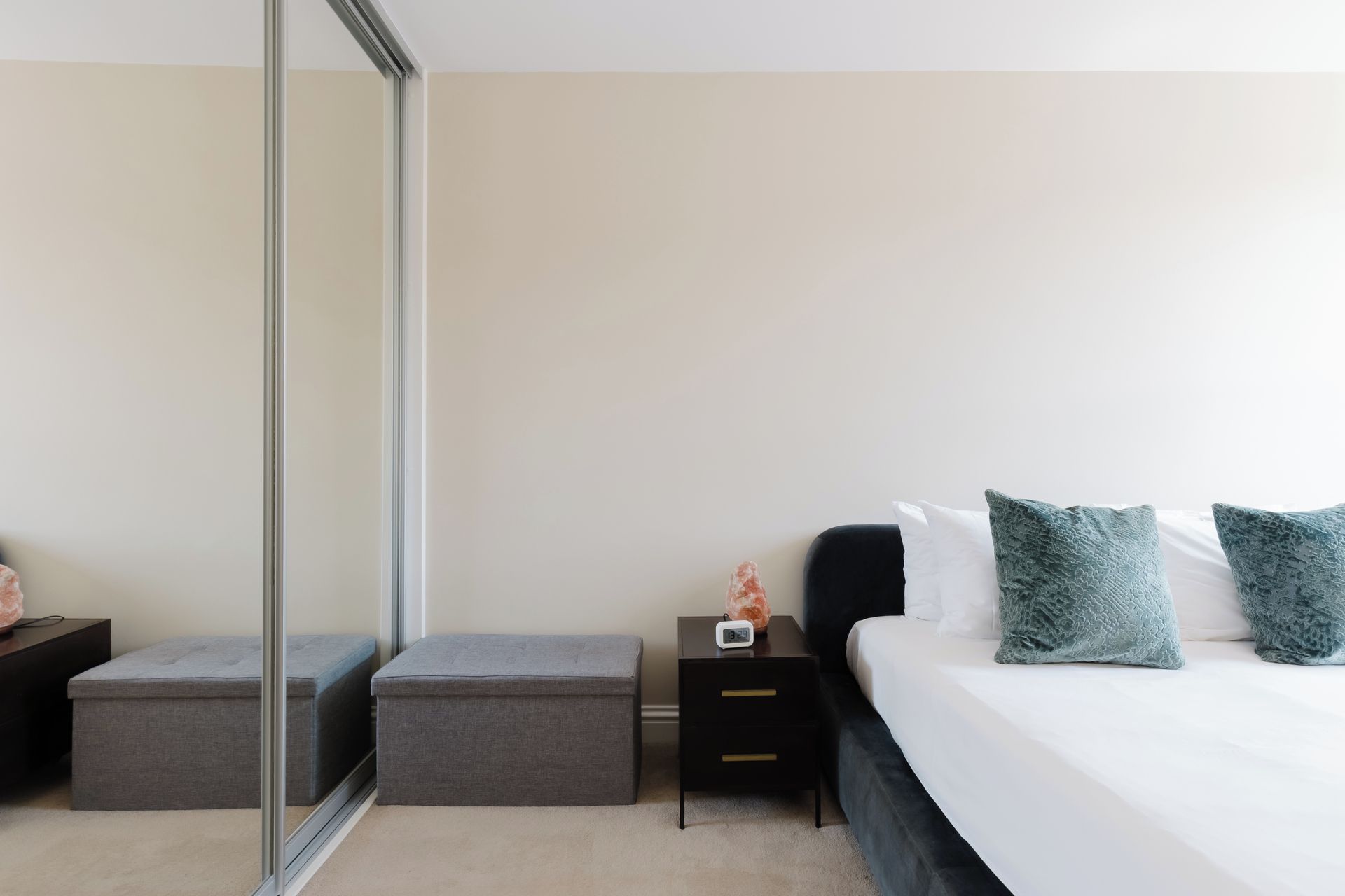 A bedroom with a bed, two nightstands, a mirror, and a sliding door.