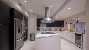A modern kitchen with a central island, stainless steel appliances, and recessed lighting. - Villa Azur by Glam Homes (North Miami Beach)
