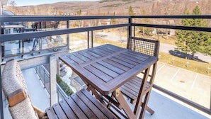 Un balcon avec une table et des chaises, donnant sur un paysage montagneux.
