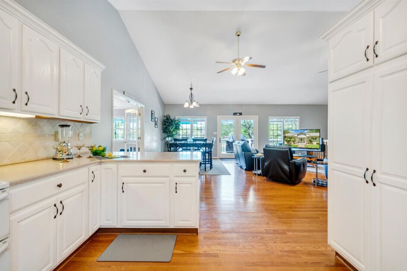 A spacious kitchen with white cabinets, a central island, and a ceiling fan.