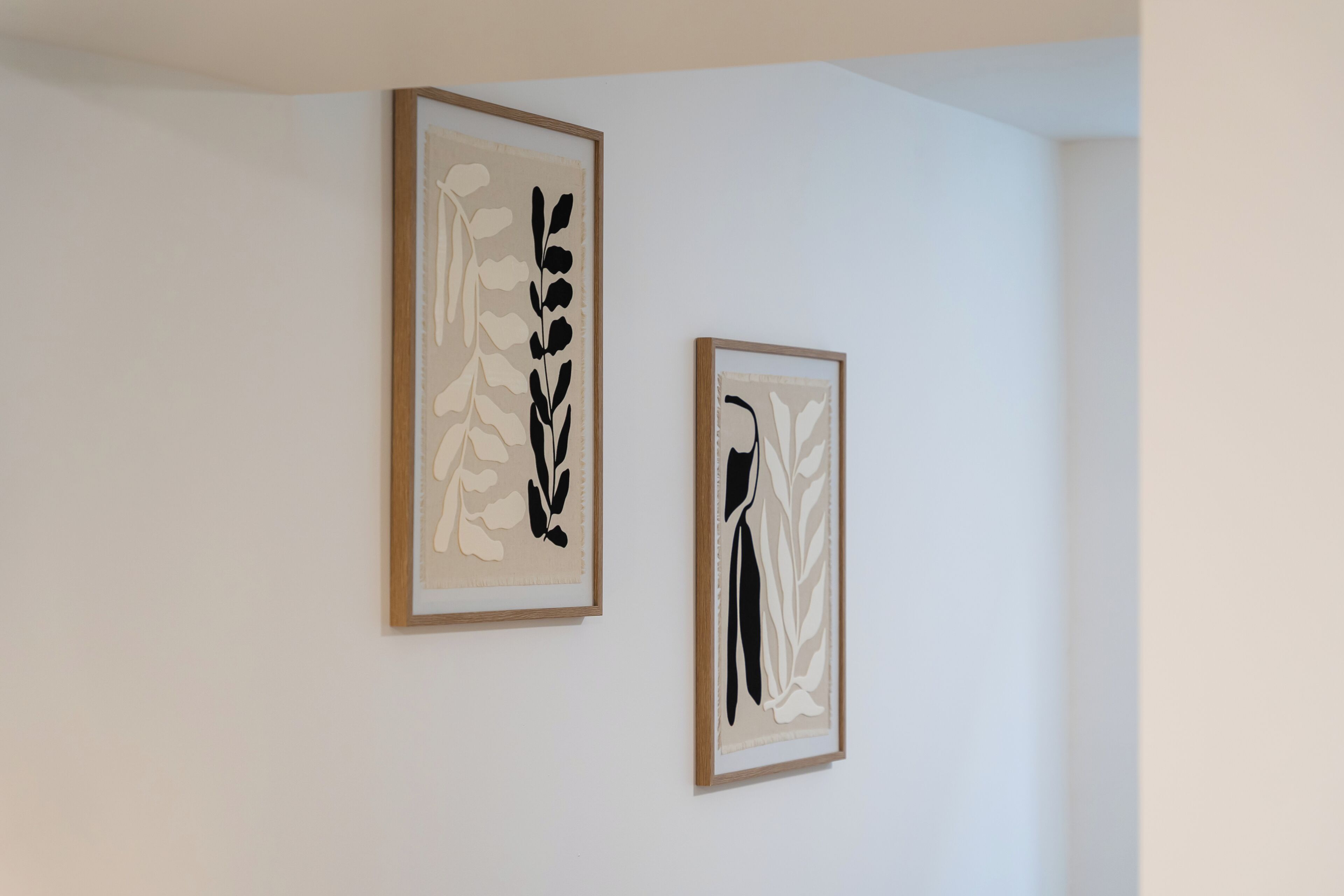 Two framed abstract art pieces on a plain white wall.