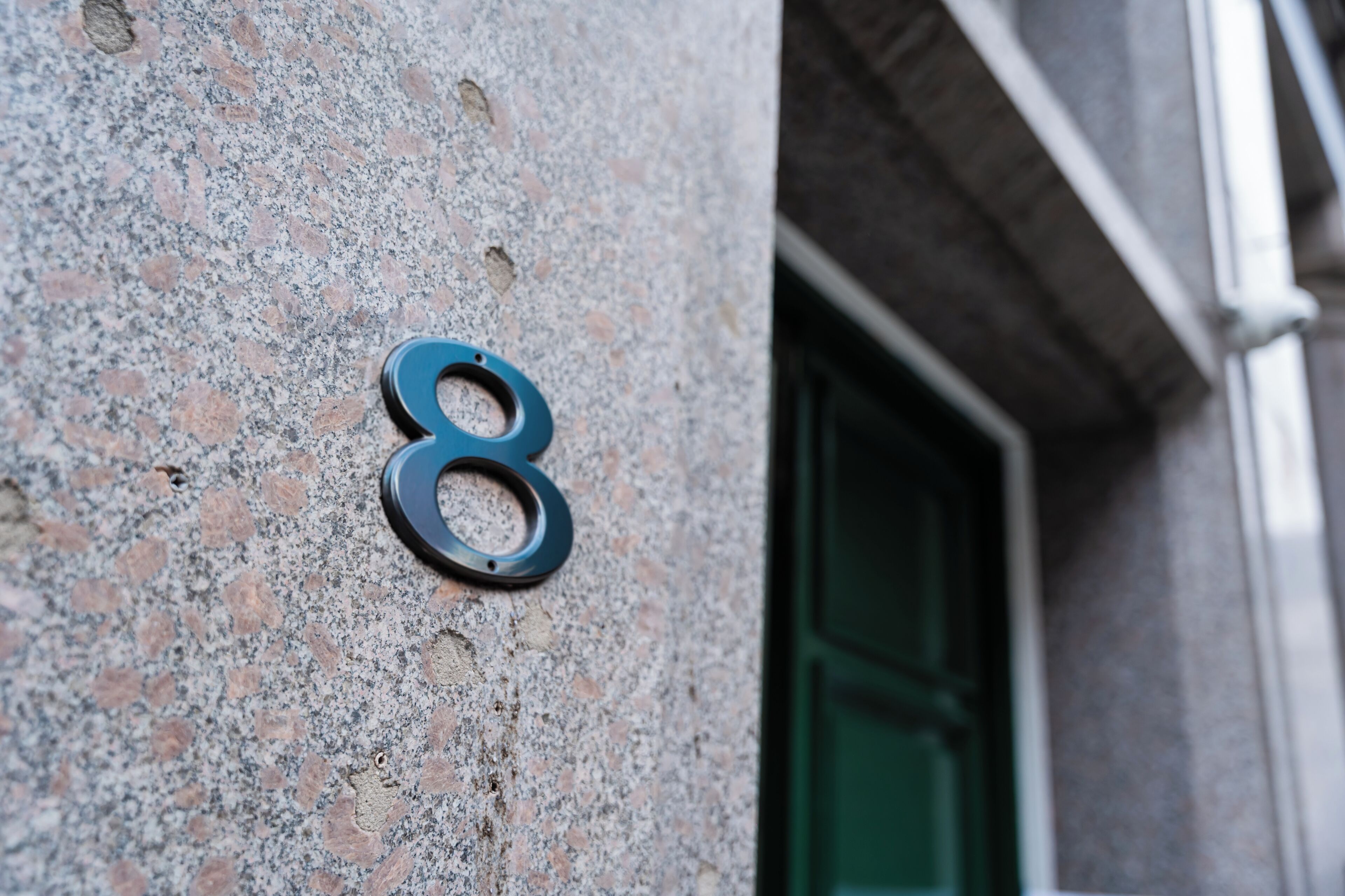 A building facade with a number '8' sign on a textured wall.