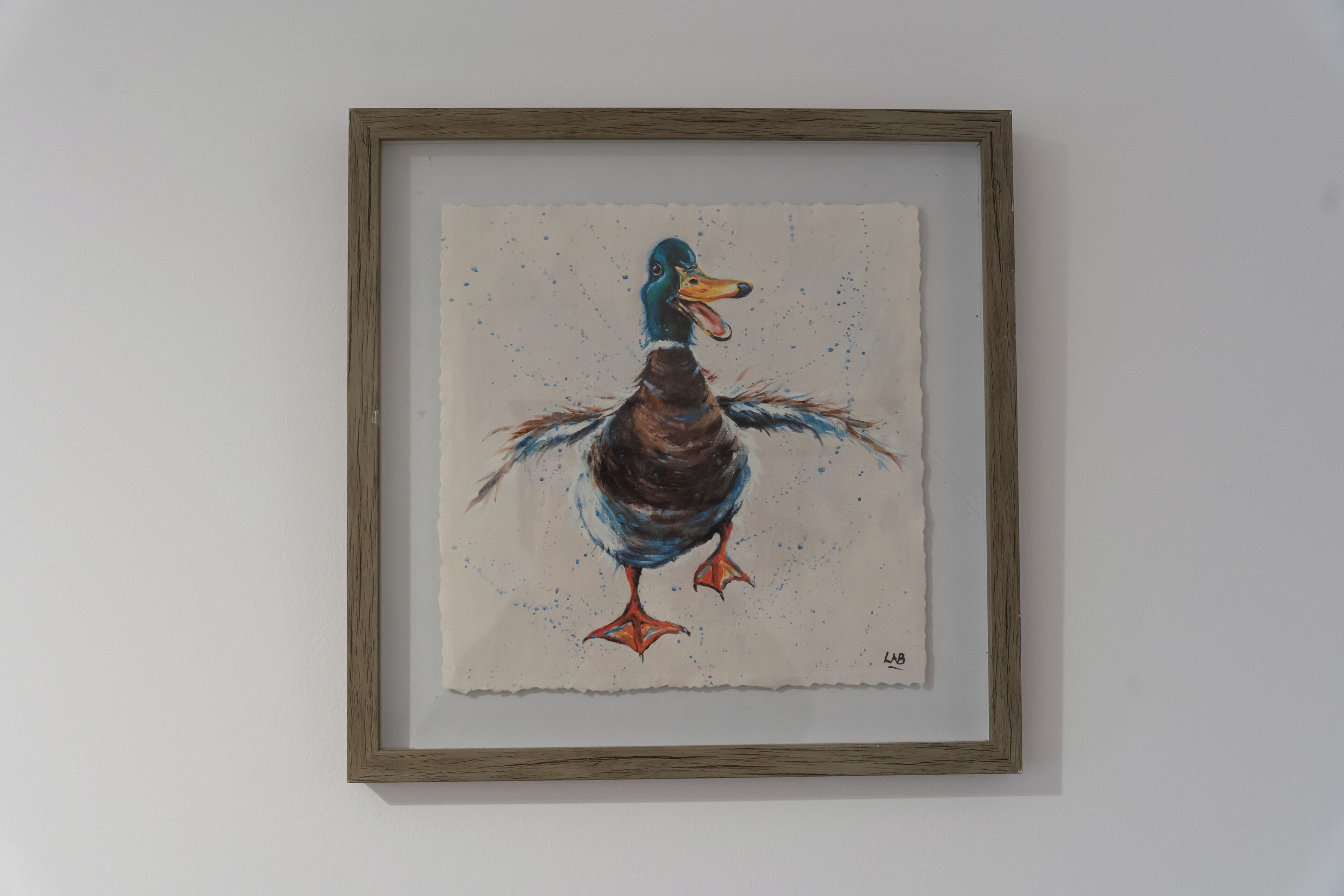 Een lijst met een afbeelding van een eend aan een effen muur.