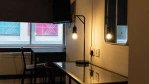 A modern kitchen with a glass table, black chairs, a mounted TV, and a wall-mounted light fixture. - 8 Stanley Street (Liverpool)
