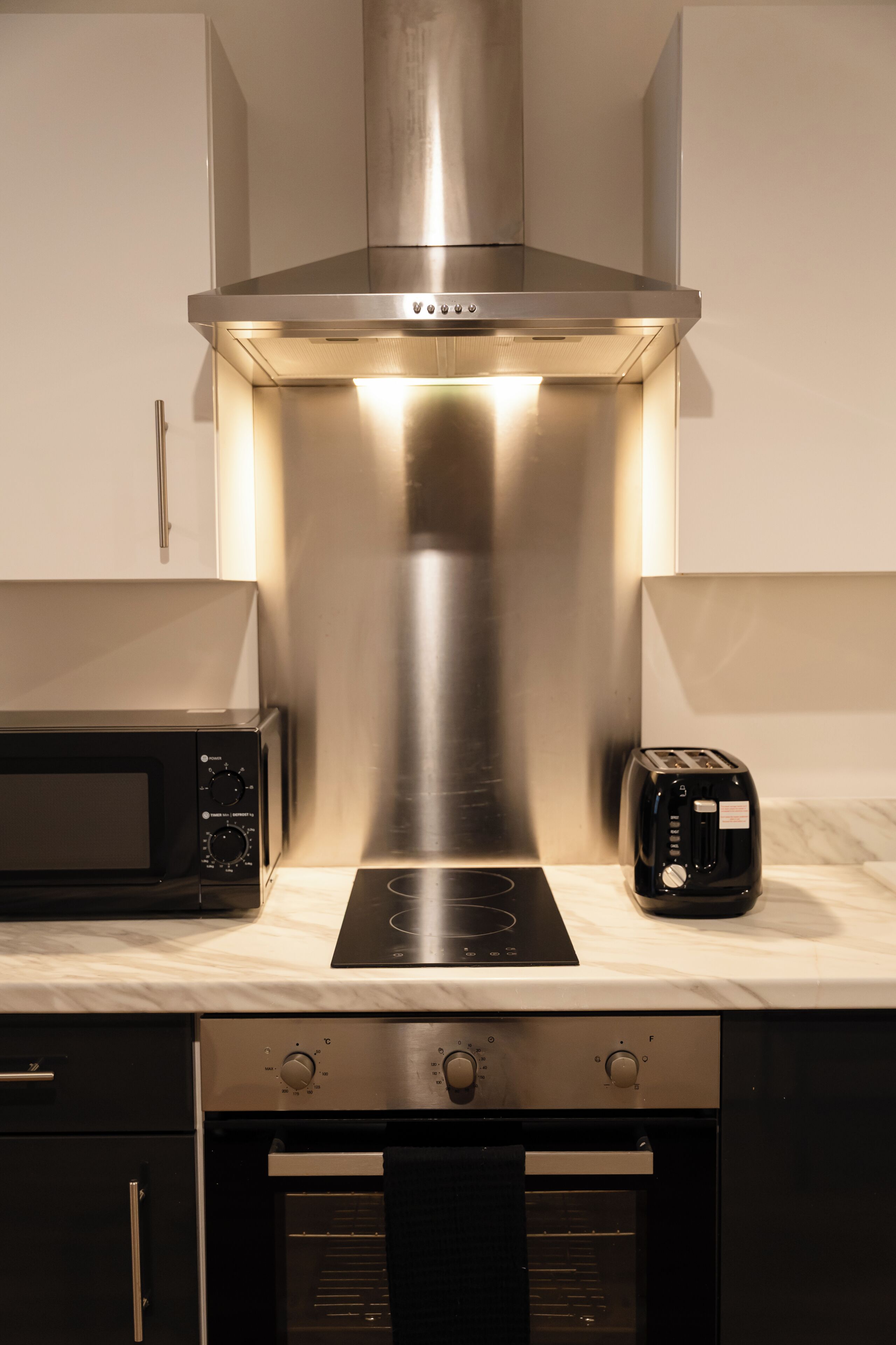 A kitchen with a stainless steel range hood, a microwave, a toaster, and an oven.