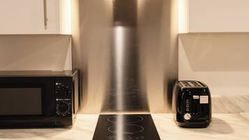 A kitchen with a stainless steel range hood, a microwave, a toaster, and an oven.