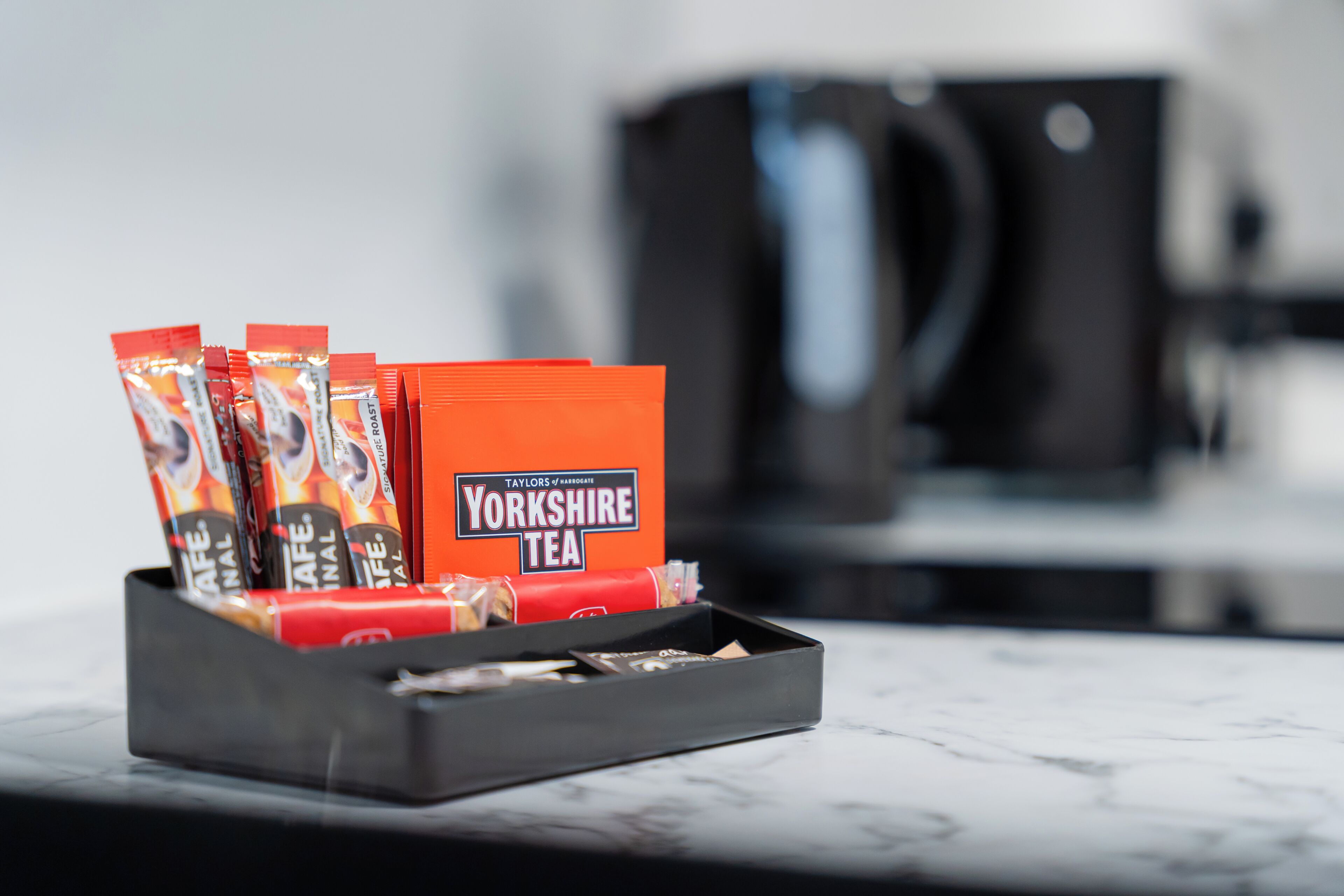 Ein Tablett mit Yorkshire Tea Teebeuteln und einer Schachtel, platziert auf einer Marmorplatte vor unscharfem Hintergrund.