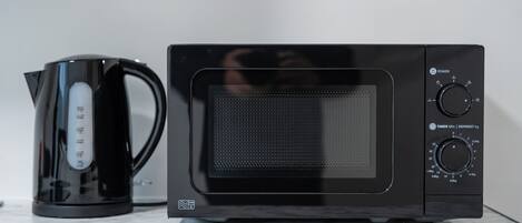 A black microwave oven with a digital display and control knobs on a marble countertop.