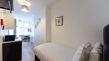 Un dormitorio con una cama, un escritorio y una silla.