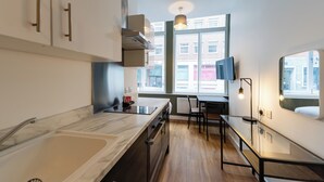 A modern kitchen with a marble countertop, a built-in oven, and a window with a view of buildings. - 8 Stanley Street (Liverpool)
