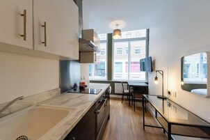 Una cocina moderna con encimera de mármol, horno integrado y ventana con vistas a edificios.