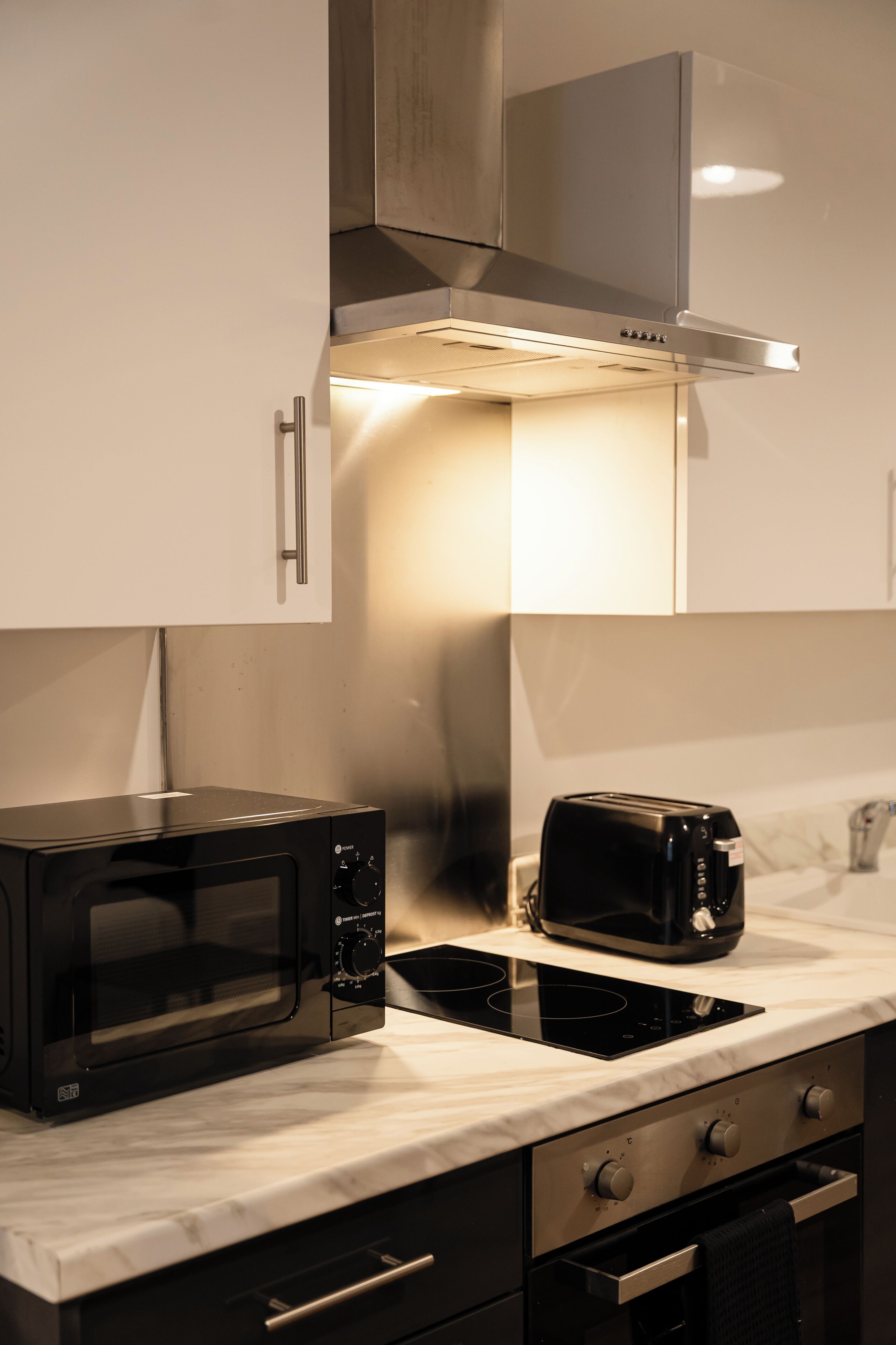A modern kitchen with a microwave, toaster, and stainless steel range hood.