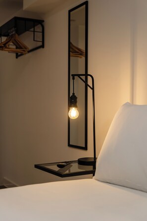 A bed with a white pillow, a bedside table with a lamp, and a wall-mounted mirror. - 8 Stanley Street (Liverpool)