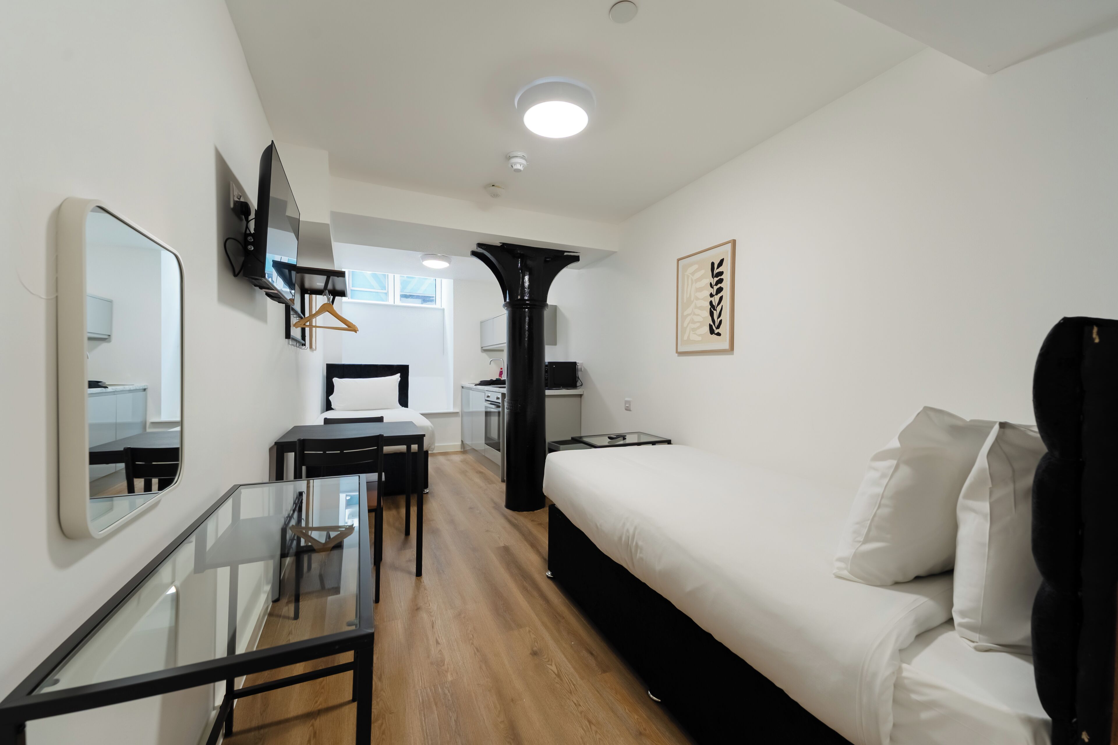 Een moderne hotelkamer met een bed, een bureau, een stoel, een televisie en een spiegel.