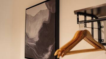 A framed abstract artwork on a wall, a wooden hanger, and a black metal rack.