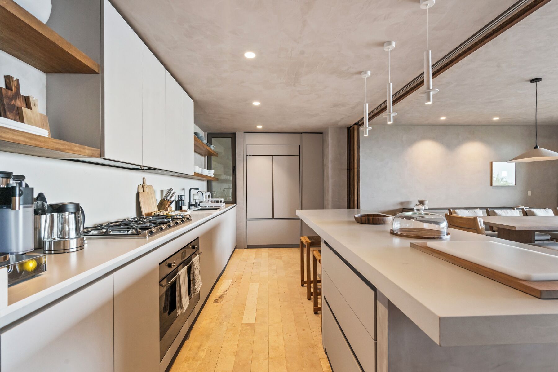 A modern kitchen with a central island, built-in oven, and stainless steel appliances.