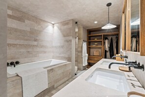 Un baño moderno con una bañera grande, un lavabo doble y un tocador de madera.