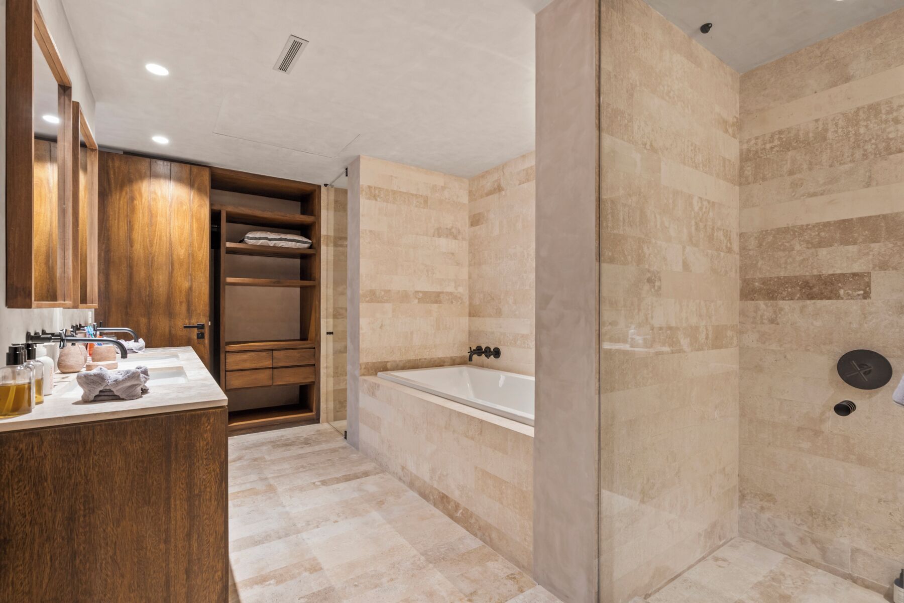 Un baño moderno con una bañera grande, ducha a ras de suelo y tocador de madera con lavabo.