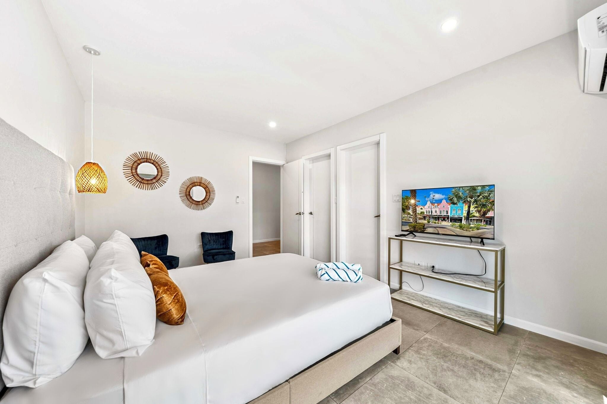 A bedroom with a bed, a TV on a stand, and a door leading to another room.