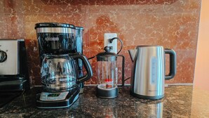 Et køkken med kaffemaskine, blender og elkedel på en granitbordplade.