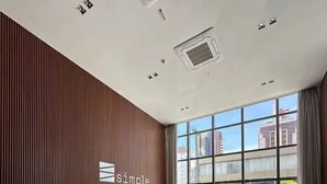 A modern reception area with a wooden panel wall, a reception desk, seating, and large windows offering city views. - Simple Smart - Miramar Hospedagens (João Pessoa)