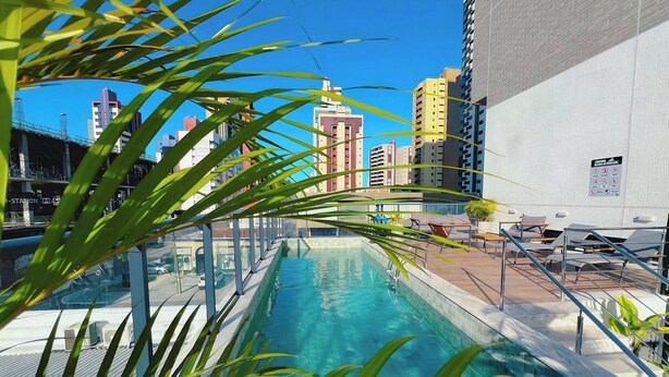 A rooftop pool with a view of high-rise buildings, a signboard, and outdoor seating. - Simple Smart - Miramar Hospedagens (João Pessoa)