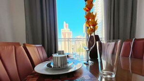 A dining table with a cake, wine glasses, and cutlery, set against a view of buildings. - Simple Smart - Miramar Hospedagens (João Pessoa)