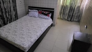 Un dormitorio con cama, cortinas y piso de baldosas.
