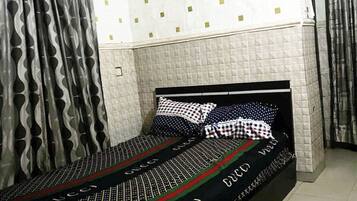 Una cama individual con una colcha estampada, un cabecero y un almohadón de diseño escocés.
