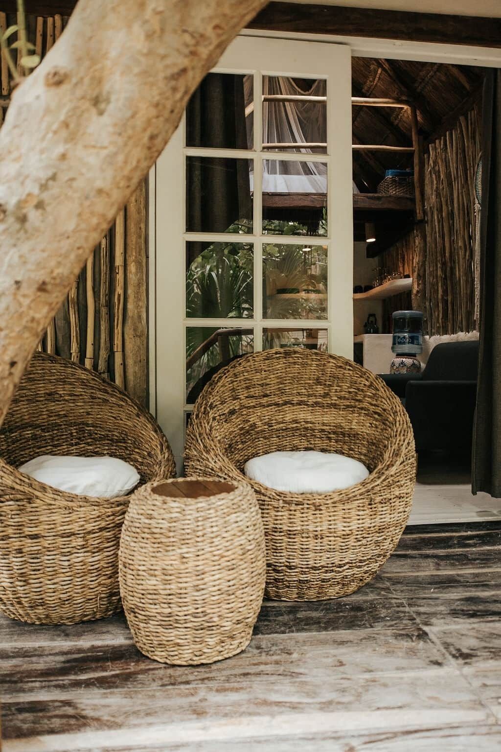 Wicker furniture with cushions, a wooden floor, and a view of a room with a glass door.