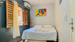 A bedroom with a bed, white curtains, a painting, and an air conditioning unit. - Pousada Anauá - Jericoacoara (Jijoca de Jericoacoara)