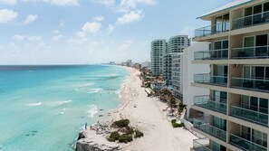 A coastal hotel with a beach view, multiple balconies, and a clear sky. - Ocean View Studio Beachfront in Hotel Zone (Cancun)