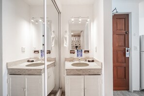 A bathroom with two sinks, a mirror, and a wooden door. - Ocean View Studio Beachfront in Hotel Zone (Cancun)