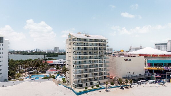 A high-rise hotel with a pool, beach, and city skyline in the background. - Ocean View Studio Beachfront in Hotel Zone (Cancun)