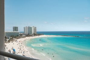 A beach with clear turquoise waters, a sandy shore, and several high-rise buildings in the background. - Ocean View Studio Beachfront in Hotel Zone (Cancun)