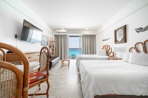 A hotel room with two beds, a TV, a small table, and a view of the sea. - Ocean View Studio Beachfront in Hotel Zone (Cancun)