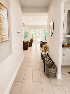 A hallway with a bench, a wicker basket, and a dining area with a table and chairs.