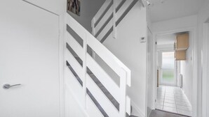 Un escalier avec des rampes blanches menant à une pièce dotée d’une porte et d’une petite fenêtre.