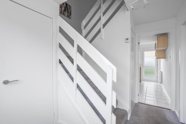 A staircase with white railings leading to a room with a door and a small window.