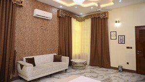 A room with a sofa, a round table, a chandelier, and curtains. - The Most Luxurious Private Resort in Karachi (Karachi)