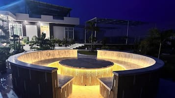 Un área de estar al aire libre circular con una chimenea central, rodeada por una cerca de madera.