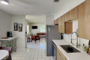 A modern kitchen with a refrigerator, sink, and dining area. - Endless Sunny Daze (St. Augustine)
