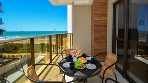 Een balkon met een tafel gedekt voor twee, met uitzicht op een strand.