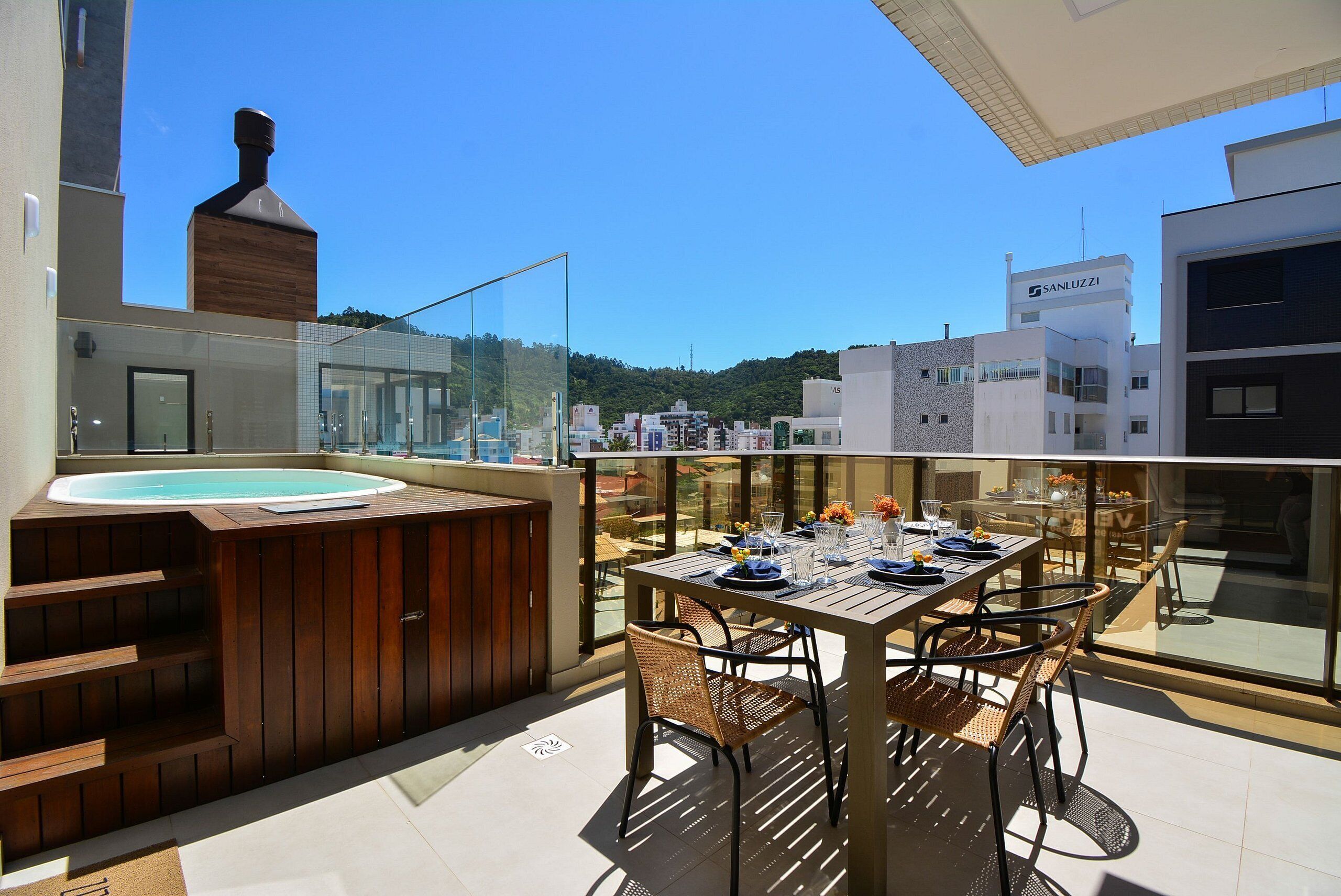 Eine Dachterrasse mit Whirlpool, Esstisch, Stühlen und Blick auf die Stadt.