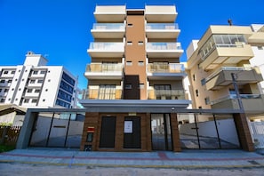 A multi-story residential building with balconies, a central brown section, and a gated entrance. - Duplex Vista Mar com Piscina Privativa  (Governador Celso Ramos)