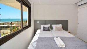 Een hotelkamer met een bed, een raam met uitzicht op zee en een airconditioning aan de muur.
