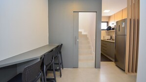 Eine schmale Küche mit Essbereich, einem Kühlschrank und einer Treppe, die zu einer weiteren Ebene führt.