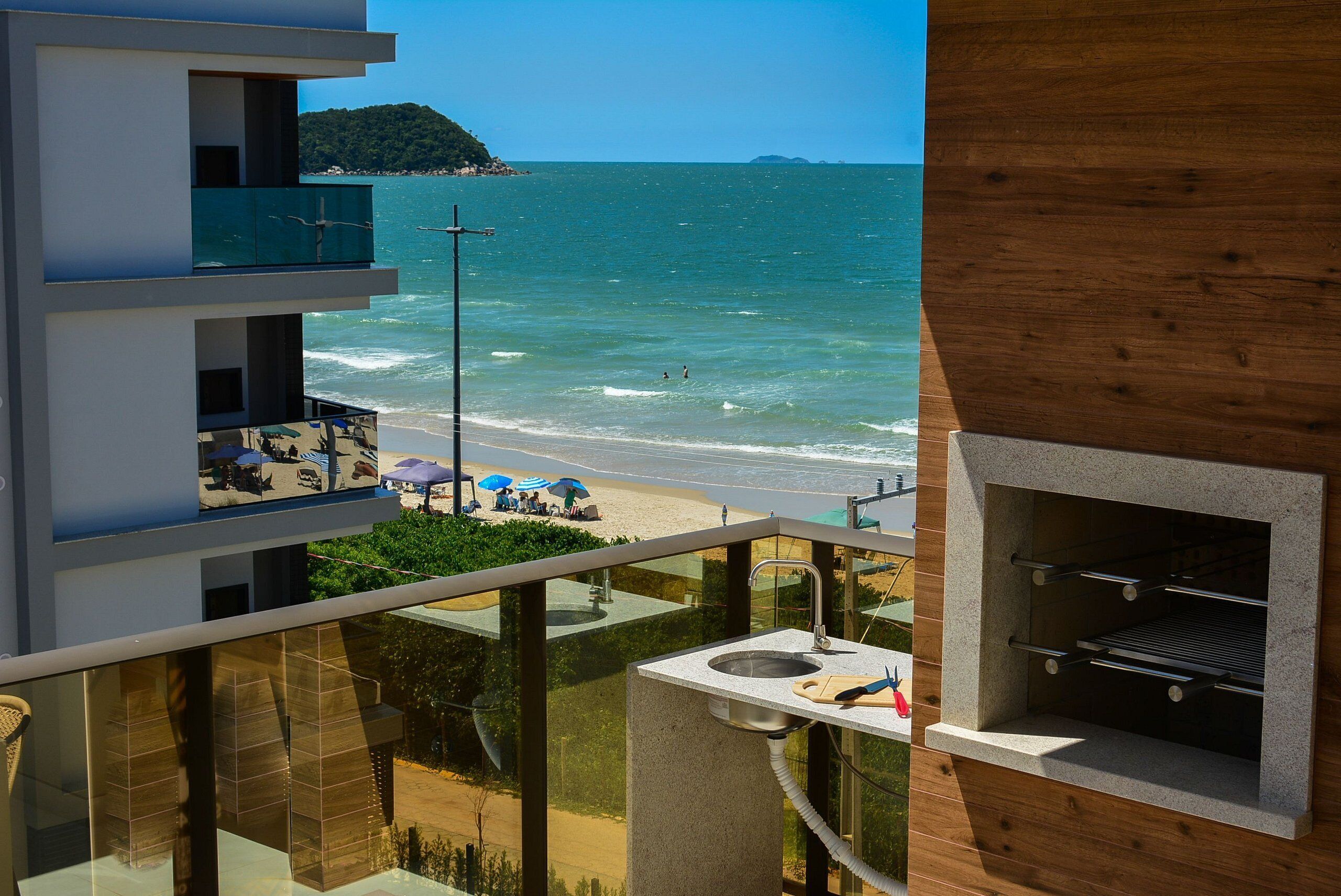 Ein modernes Gebäude mit Balkon und Meerblick, ausgestattet mit einer Küchenzeile und Grill.