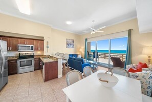 A modern kitchen with a dining area, a large window with a view of the ocean, and a ceiling fan. - Tidewater 13 (Panama City Beach)