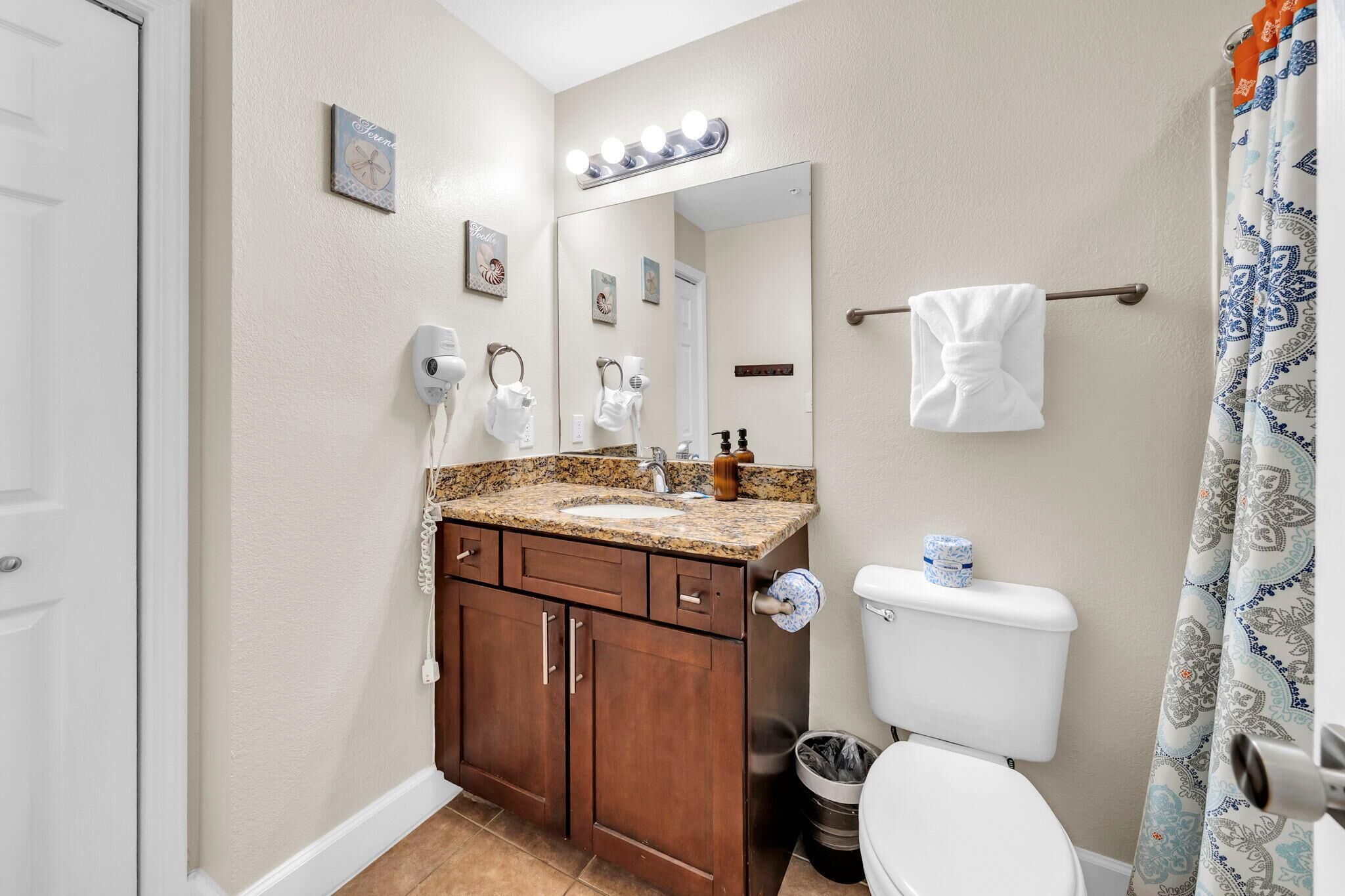 A bathroom with a vanity, sink, mirror, and toilet.